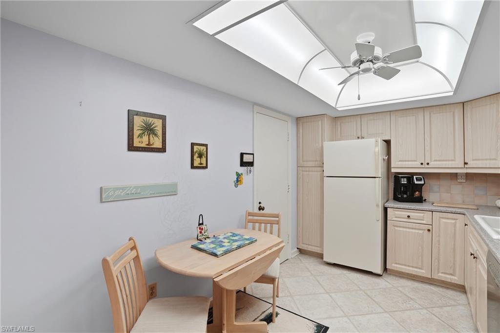 Kitchen featuring light wood-finish cabinetry, tile flooring, and a recessed ceiling with a central fan light fixture