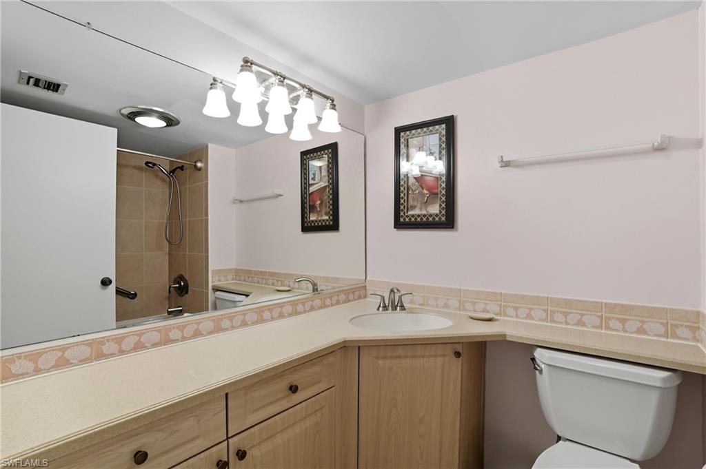 Bathroom featuring a single basin vanity with wood-finish cabinetry, a large wall mirror, and a tiled shower with a sliding door