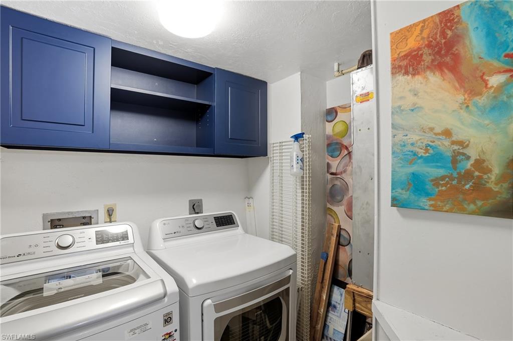 Laundry area featuring overhead blue cabinetry, integrated shelving, and white walls