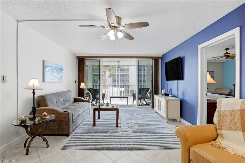 Living area featuring neutral tile flooring, a ceiling fan with integrated lighting, and a sliding glass door leading to an outdoor balcony