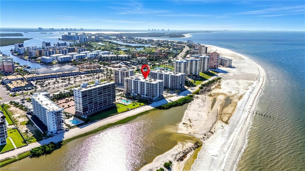 High-rise residential building situated along the coastline, featuring multiple balconies and proximity to a sandy beach