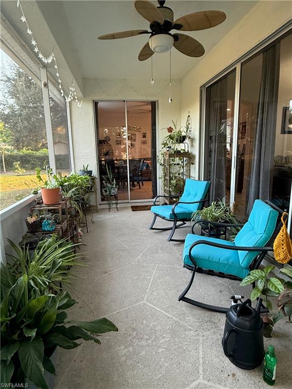 Screened patio featuring a ceiling fan with integrated lighting, concrete flooring, and sliding glass doors