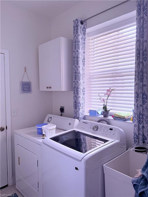 Dedicated laundry area featuring a utility sink, white wall-mounted cabinetry, and a window with blinds