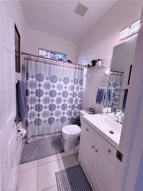Bathroom featuring tile flooring, white vanity with integrated sink, and a mirrored medicine cabinet