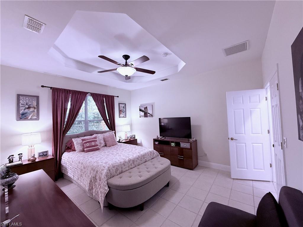 Tray ceiling with a ceiling fan, tiled flooring, window with blinds, and white paneled doors