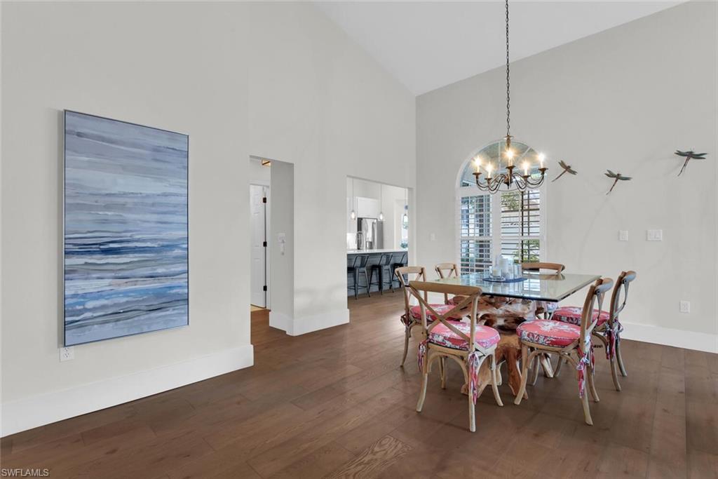 Dining space featuring a chandelier, high vaulted ceiling, and wood finished floors