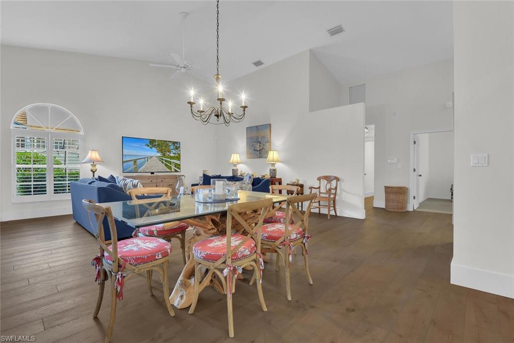 Dining room with a chandelier, hardwood / wood-style flooring, and high vaulted ceiling