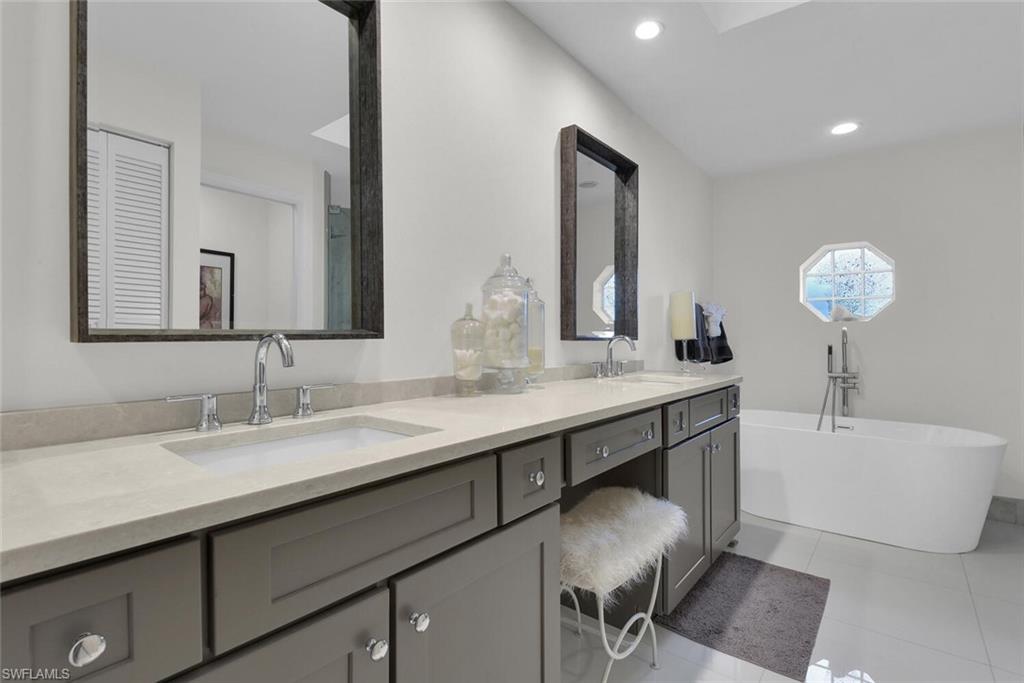 Full bathroom featuring double vanity, a freestanding tub, tile patterned floors, and recessed lighting