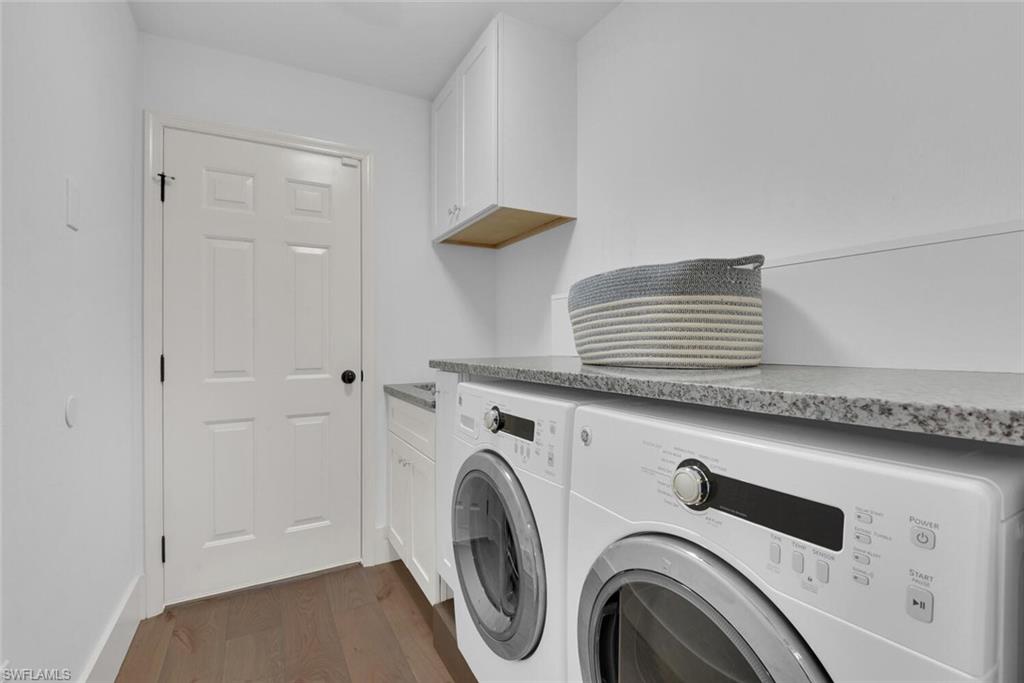 Laundry area featuring independent washer and dryer, dark wood-style flooring, and cabinet space
