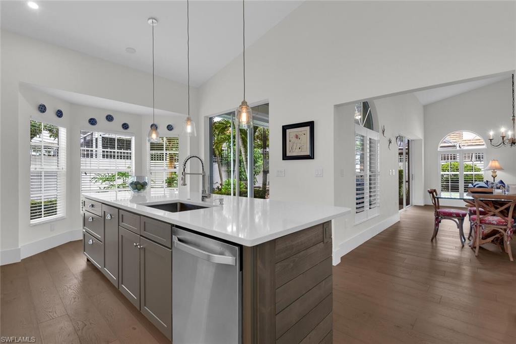 Kitchen featuring stainless steel dishwasher, gray cabinetry, light countertops, dark wood-style floors, and a chandelier