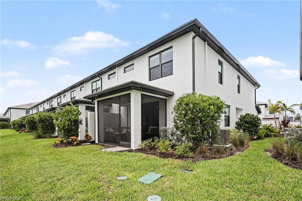 White stucco exterior featuring a screened-in lanai, dark window frames, and a dark fascia