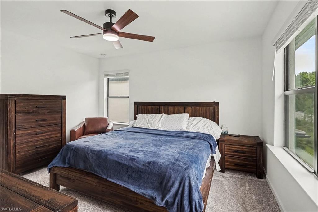 Carpeted room featuring a ceiling fan with integrated lighting, multiple windows, and light-toned walls