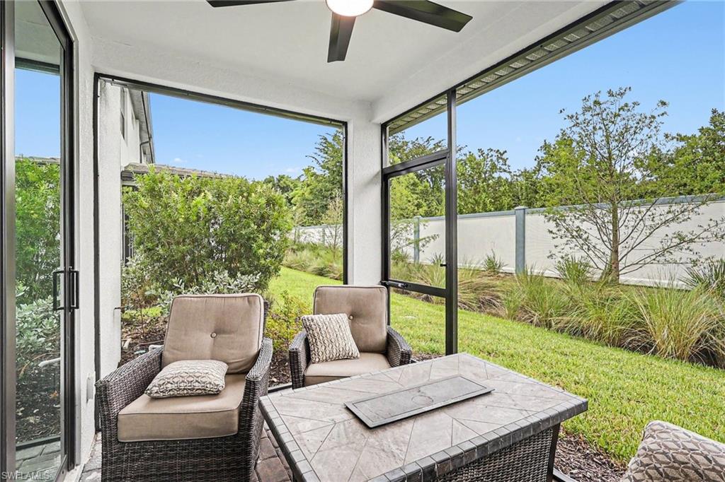 Screened patio featuring a ceiling fan, sliding glass door access, and a tiled outdoor table