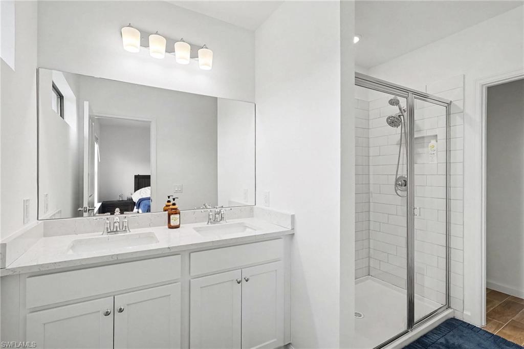 Bathroom featuring a dual vanity with white cabinetry, light-toned countertops, and a full-width mirror