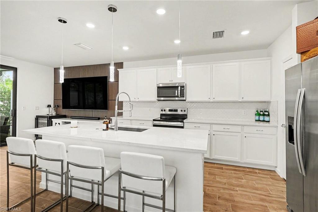 Kitchen featuring white shaker-style cabinetry, a large center island with a white countertop, and stainless steel appliances