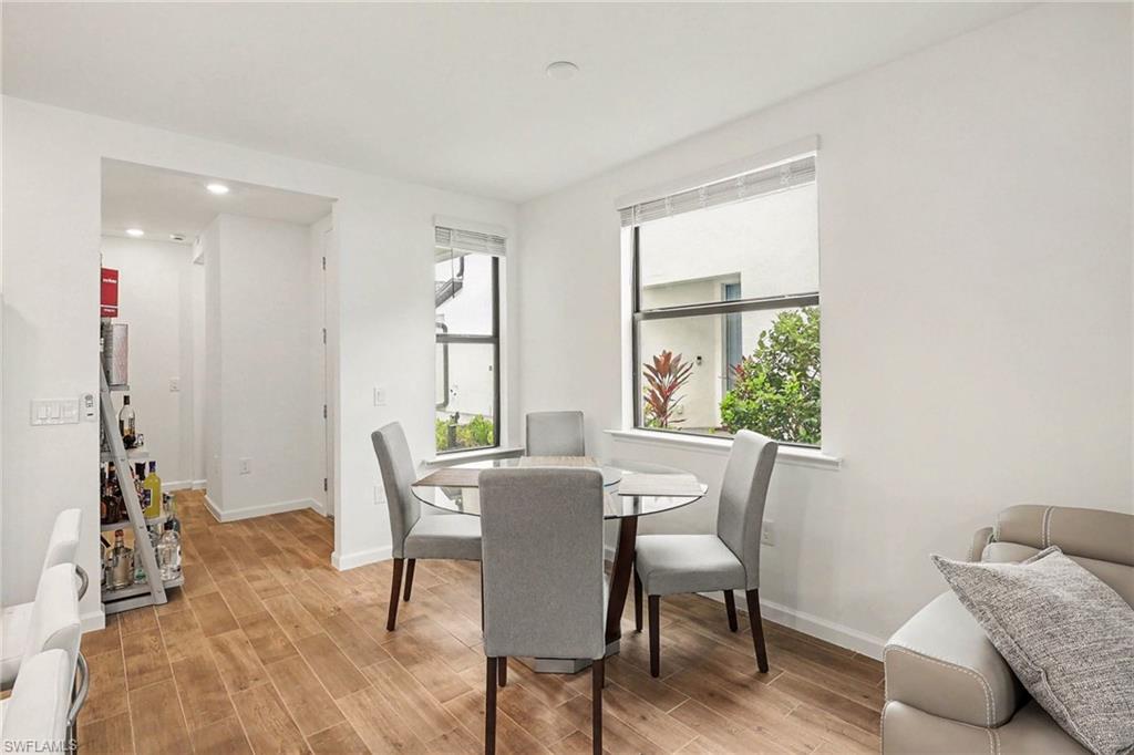 Dining area featuring wood-finish flooring, two large windows, recessed ceiling lighting, and a white baseboard trim