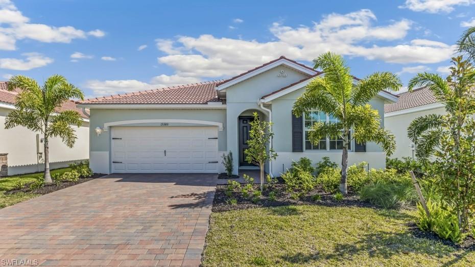 Model Home. Coastal-inspired stucco exterior featuring a terra cotta tile roof and a paver driveway