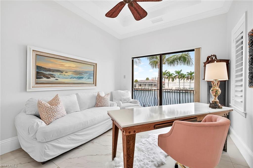 Office with a water view, a raised ceiling, a ceiling fan, crown molding, and marble finish flooring