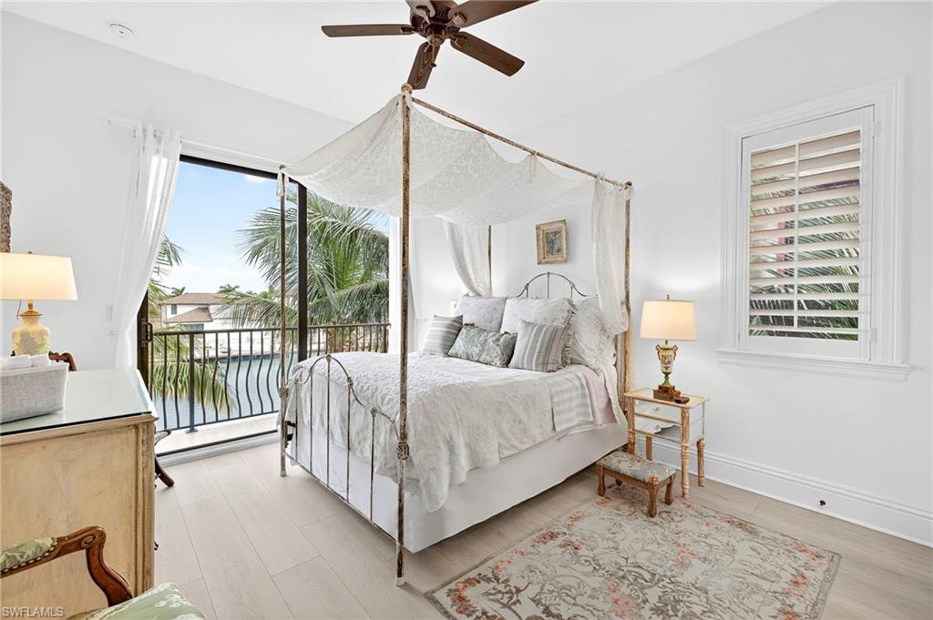 Bedroom featuring access to exterior, ceiling fan, light wood-style floors, and a water view