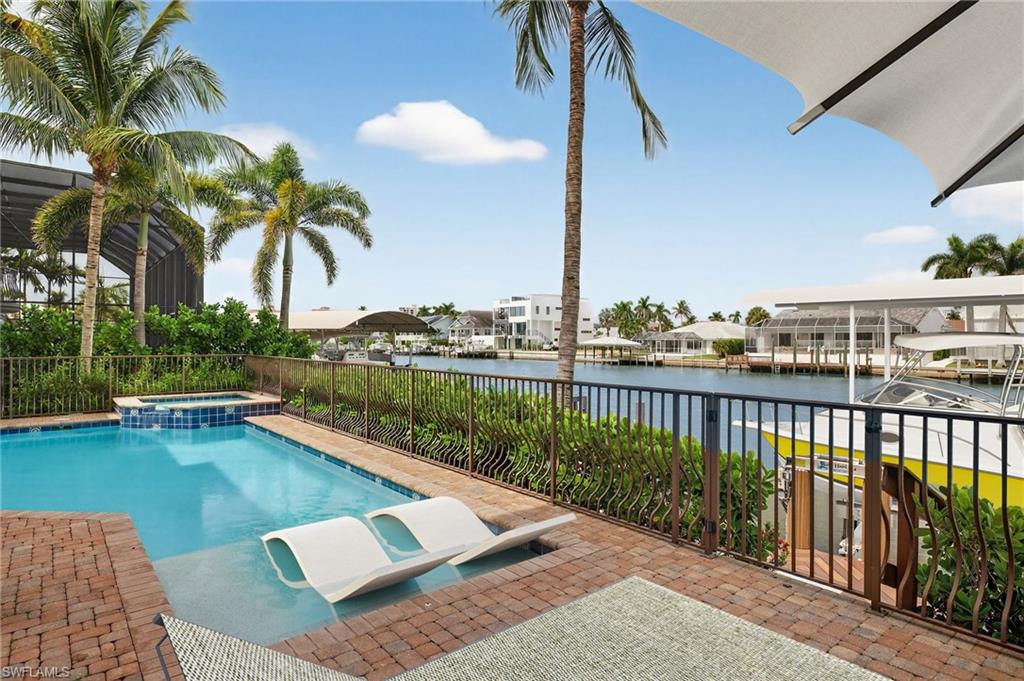 View of pool featuring a water view, a pool with connected hot tub, and a patio