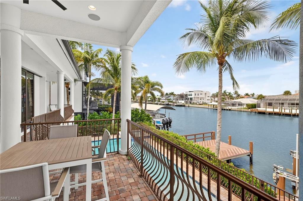 Balcony with a dock, a water view, a ceiling fan, and boat lift