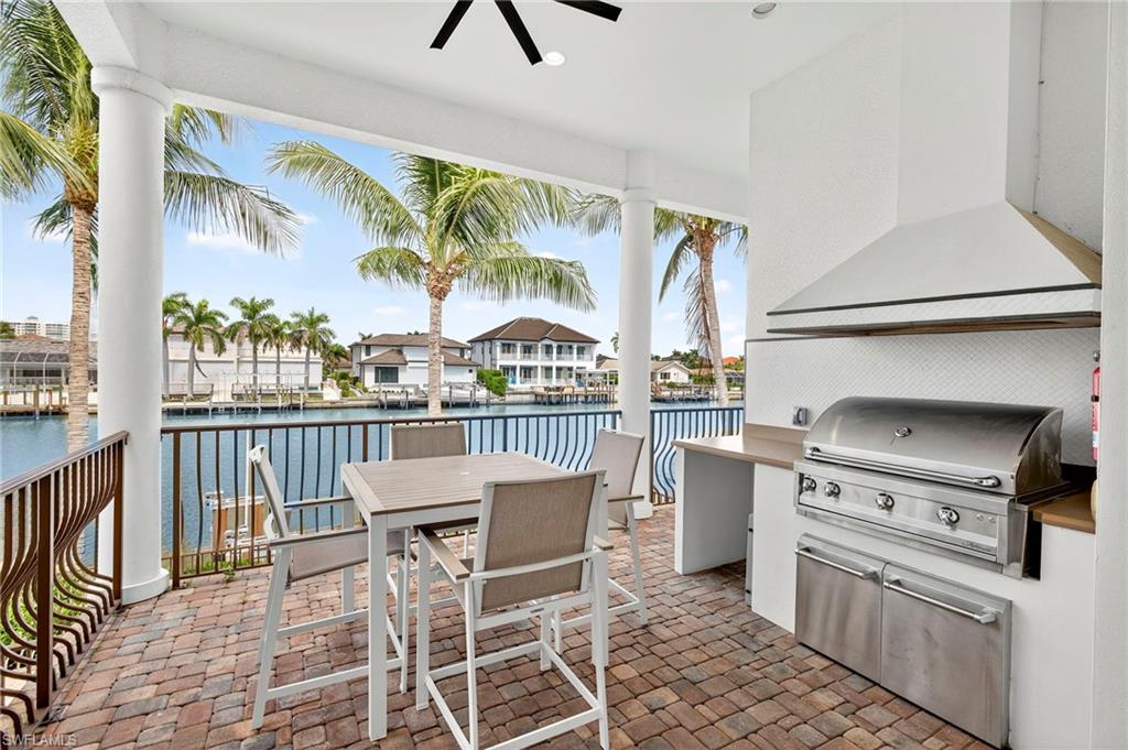View of patio / terrace featuring exterior kitchen, a water view, ceiling fan, and outdoor dining space