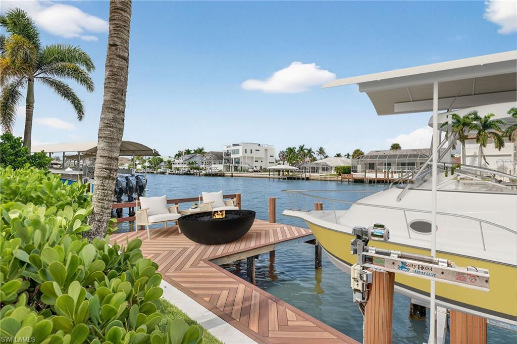 Dock with boat lift, a water view, and an outdoor fire pit