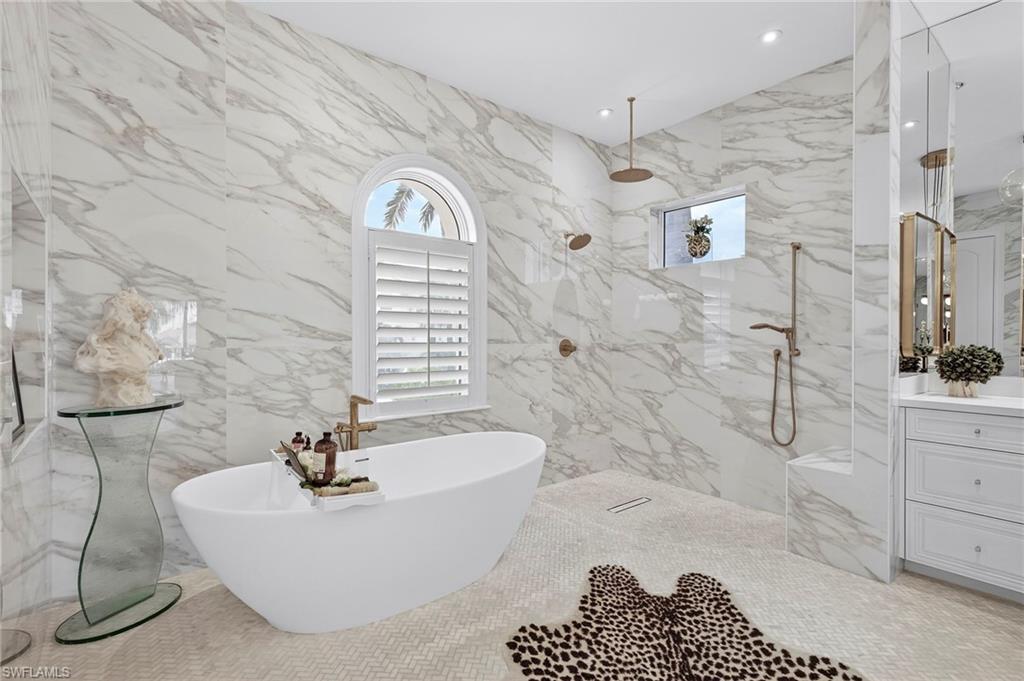 Full bathroom with a marble finish shower, vanity, stone wall, a freestanding tub, and recessed lighting