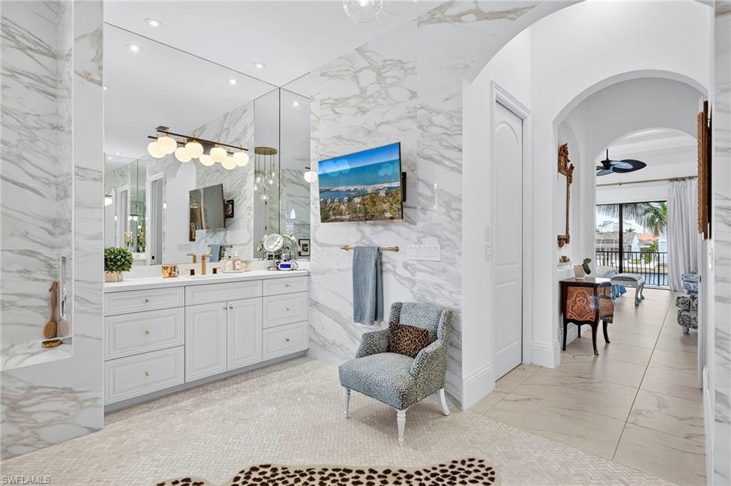 Bathroom featuring vanity, light marble finish flooring, recessed lighting, ceiling fan, and stone wall