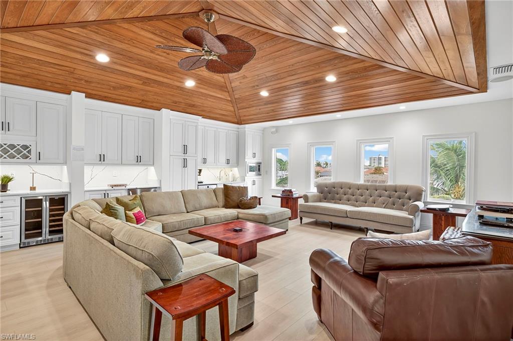 Living area with vaulted ceiling, wood ceiling, beverage cooler, recessed lighting, and a ceiling fan