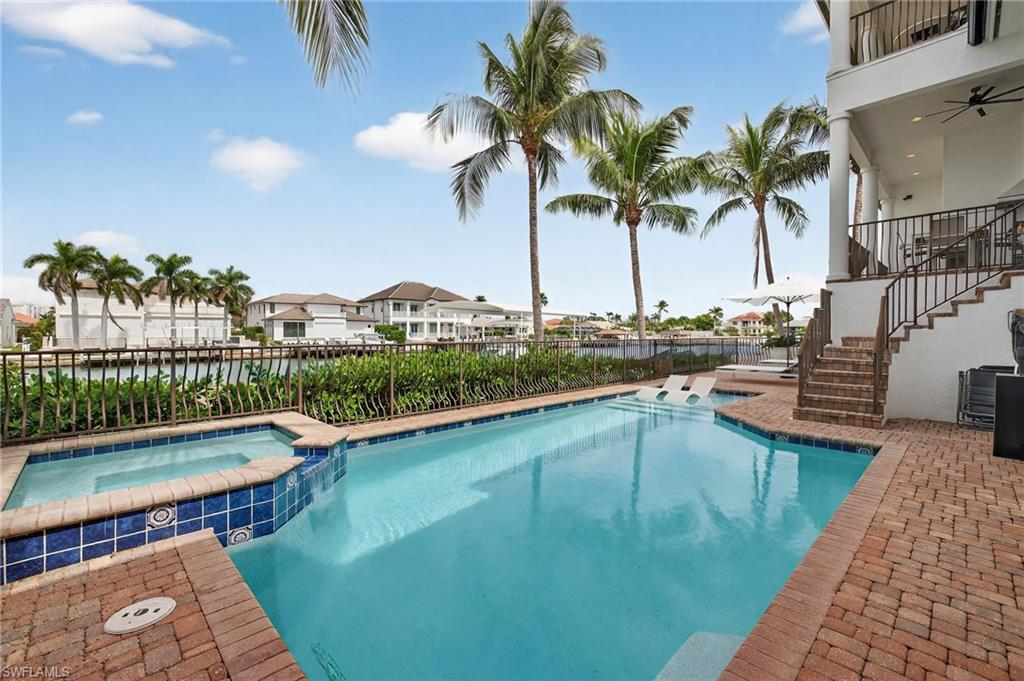 View of swimming pool featuring stairway, a patio, a pool with connected hot tub, and a balcony