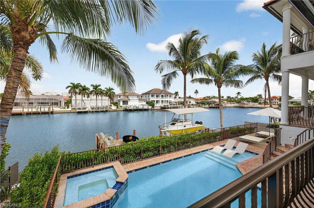 View of swimming pool featuring a pool with connected hot tub, a water view, a balcony, and a patio area