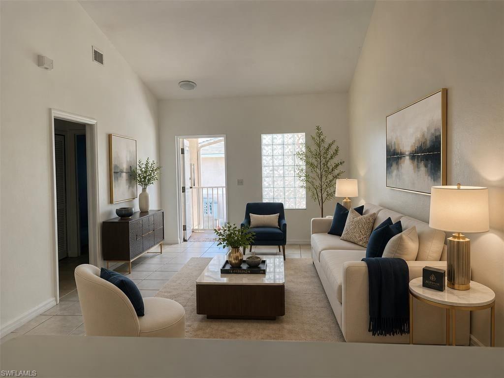 Living area featuring vaulted ceilings, light tile flooring, and a glass block window for natural light