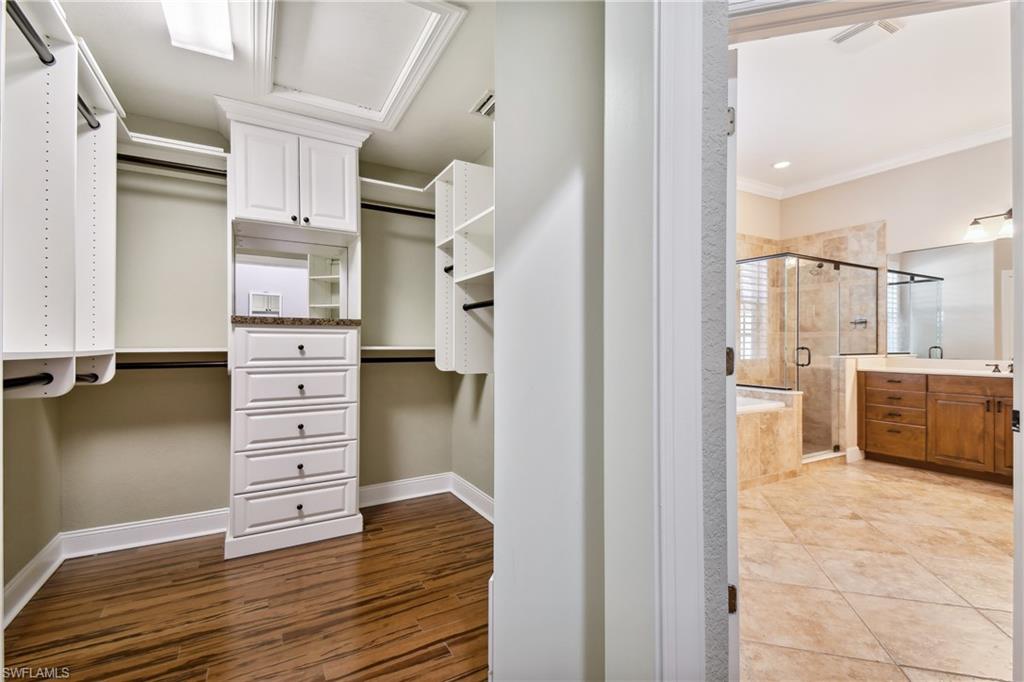 Custom closet system featuring white cabinetry, built-in drawers, and extensive shelving with ample hanging space