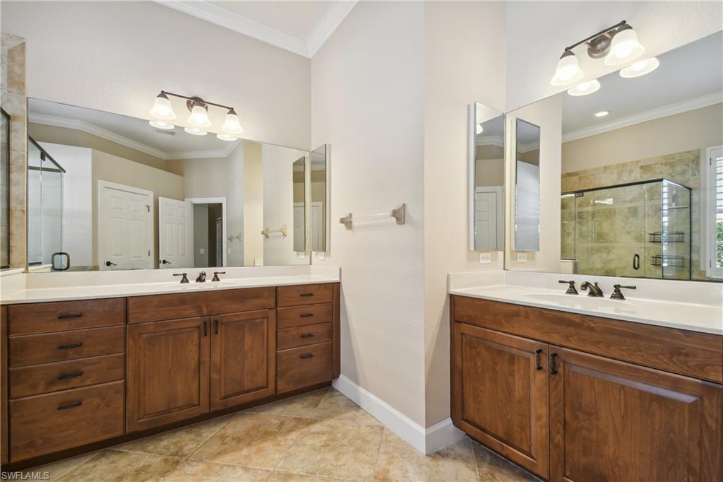 Double vanity featuring wood-finish cabinetry, white countertops, and integrated sinks