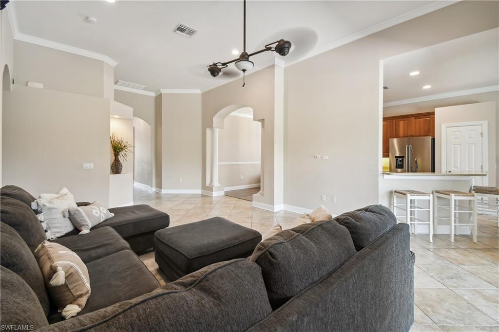 Spacious living area featuring tile flooring, crown molding, a built-in architectural niche, and recessed lighting