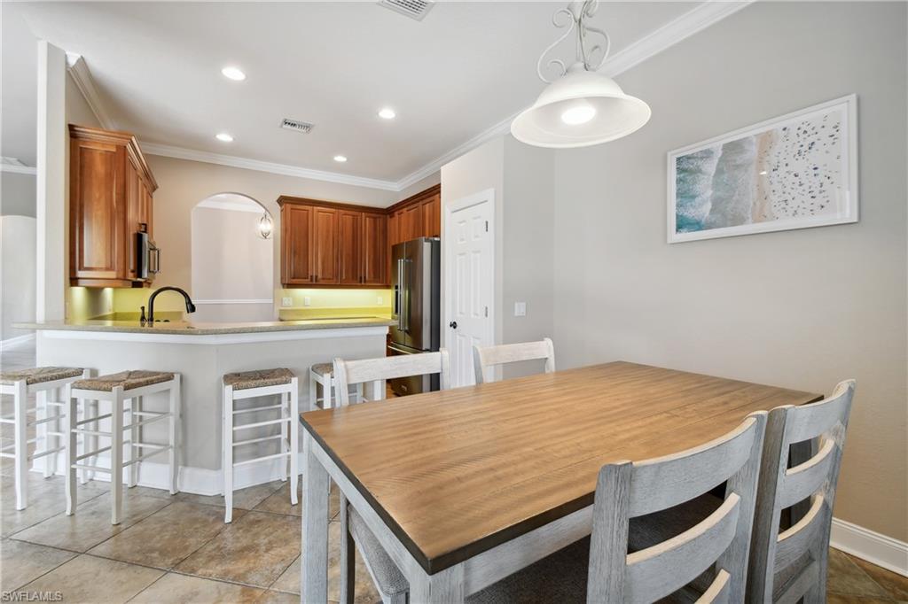 Kitchen and dining area featuring warm wood cabinetry, neutral countertops, and tile flooring