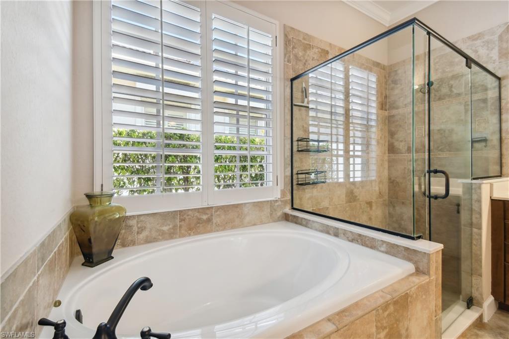 Soaking tub with bronze-finish fixtures, complemented by a glass-enclosed shower featuring tiled walls
