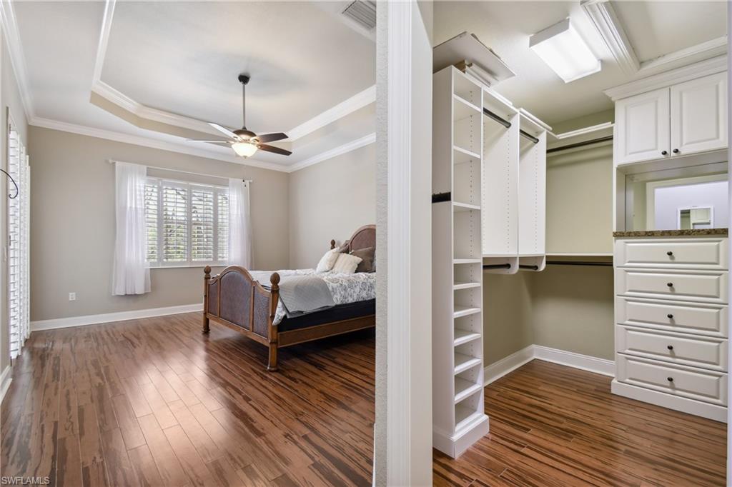 Spacious room with wood-finish tile flooring, tray ceiling, and a ceiling fan
