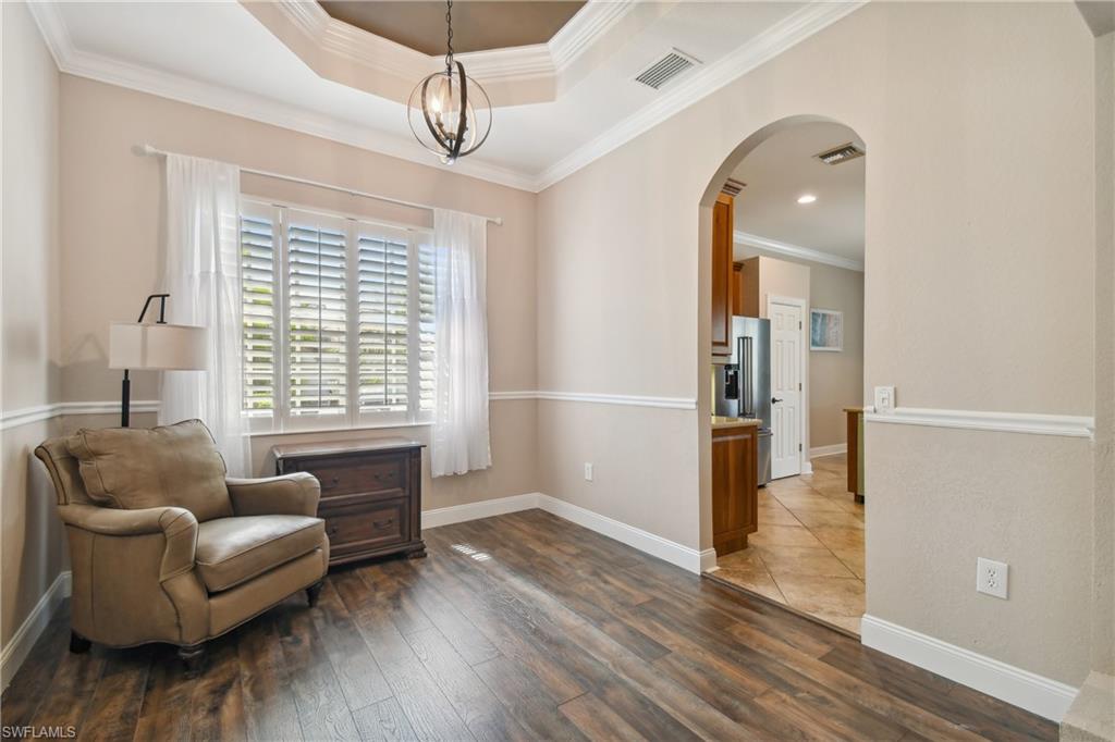 Formal room featuring wood-finish flooring and an elegant tray ceiling with a spherical chandelier