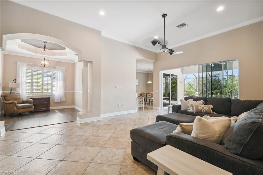 Spacious living area featuring neutral wall tones, tile flooring, and crown molding