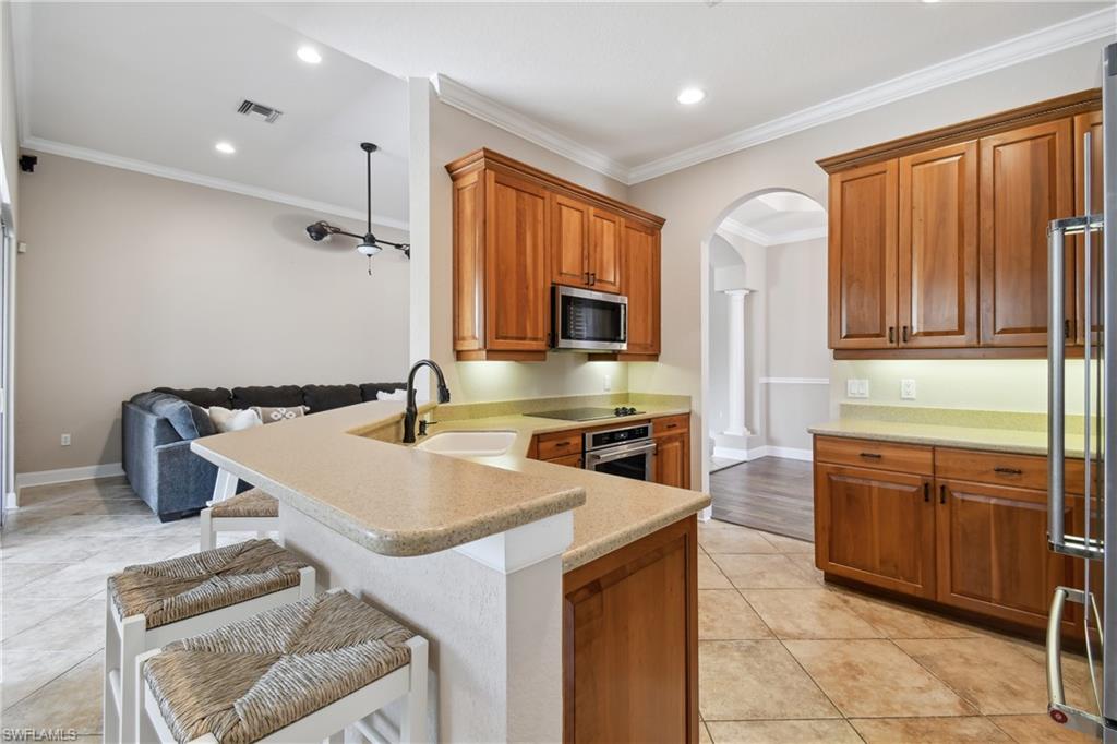 Kitchen featuring wood cabinetry, a stainless steel microwave, and tile flooring