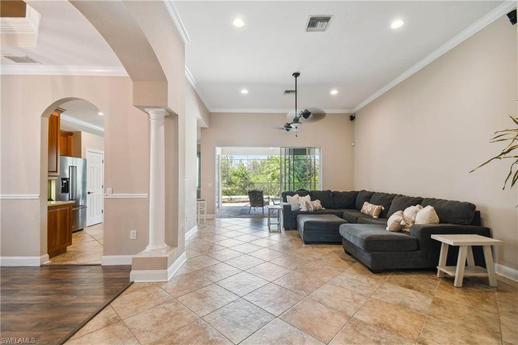 Spacious living area featuring large format tile flooring, crown molding, recessed lighting, and a ceiling fan
