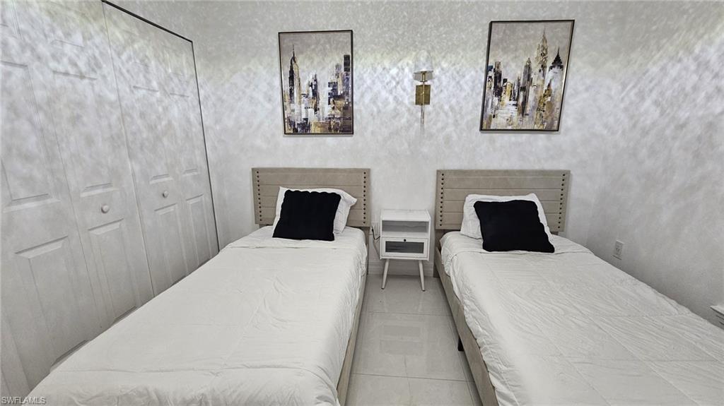 White bi-fold closet doors, light-toned walls, and tile flooring