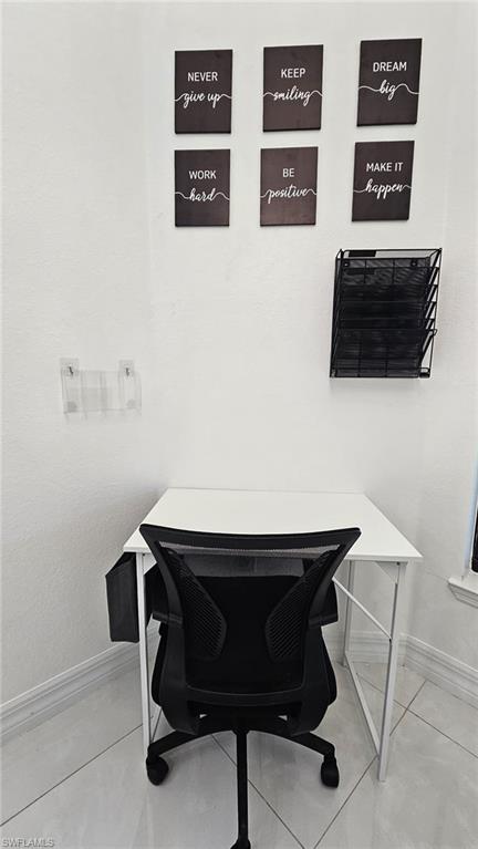 White wall space with subtle baseboard trim, featuring tiled flooring