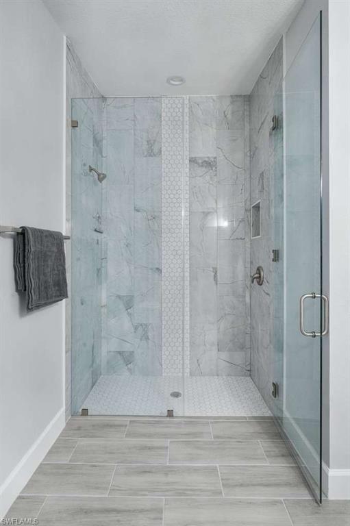 Full bathroom with a marble finish shower and baseboards