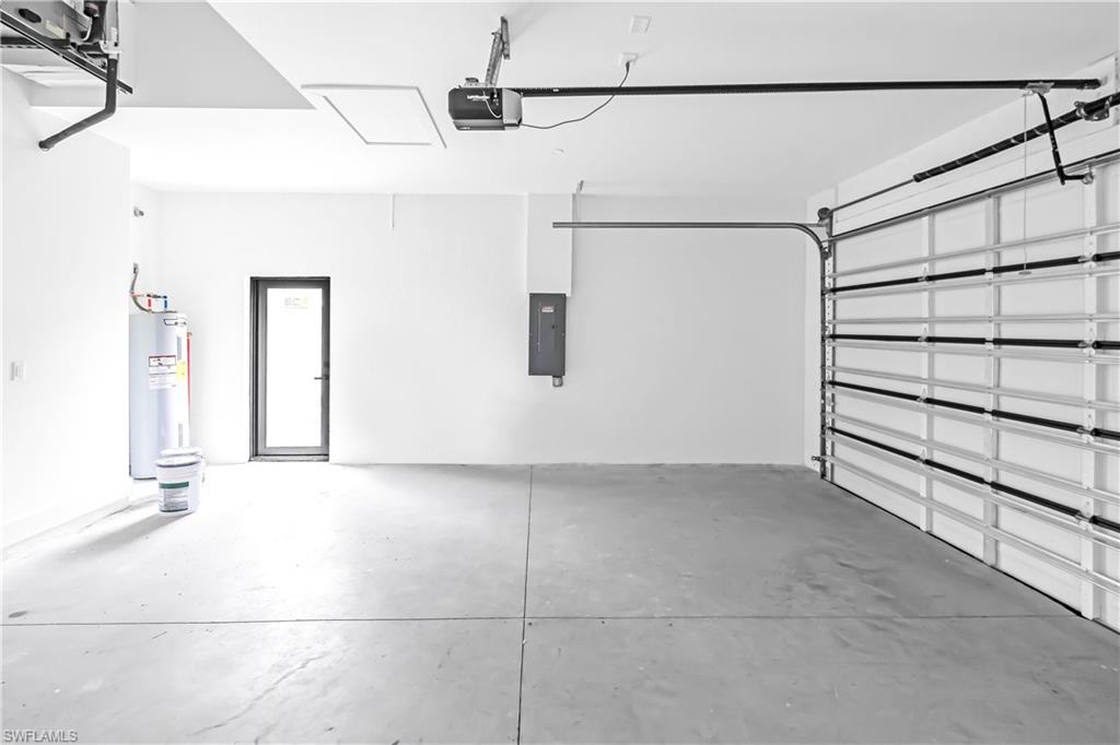 Spacious garage with a concrete floor, overhead door, and dedicated utility access