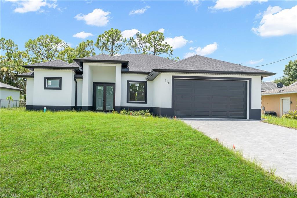 Contemporary exterior featuring a contrasting black and white color scheme, a dark gray shingle roof, double-door entryway, and a two-car garage with a matching dark gray door