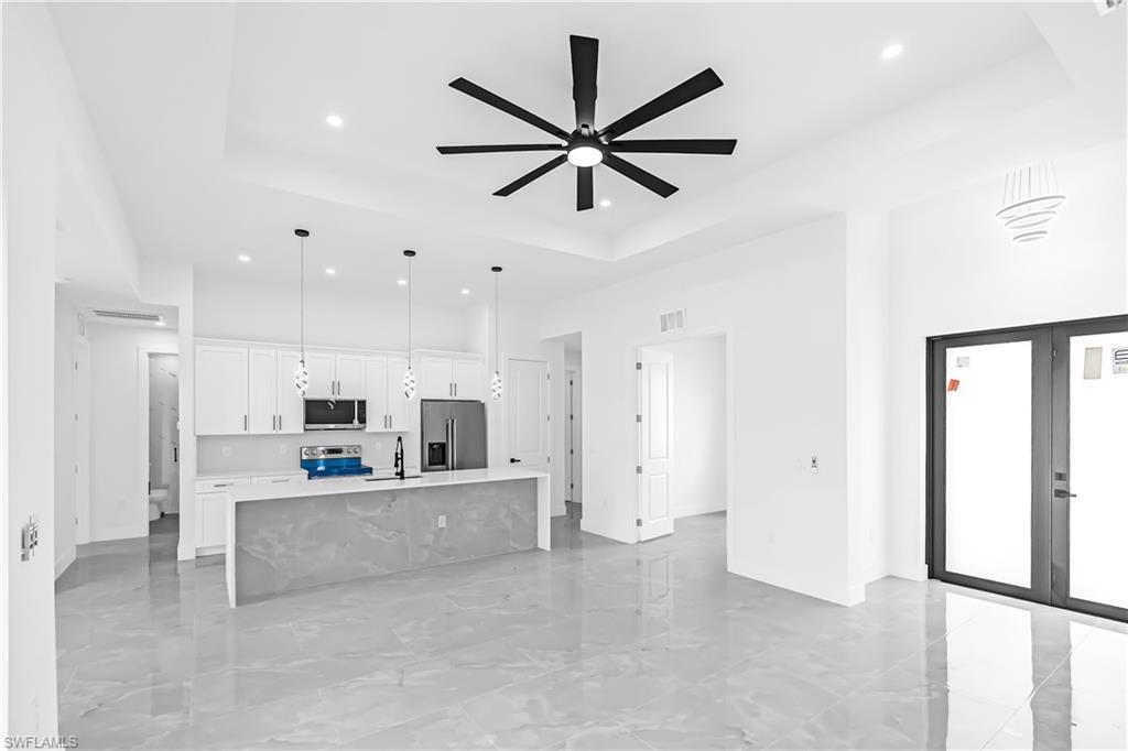 Open-concept living space featuring light gray tile flooring and a tray ceiling with a contemporary ceiling fan