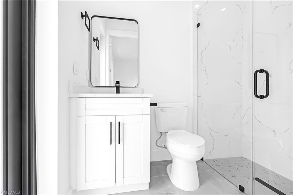 Modern bathroom featuring a white vanity with a quartz-finish countertop and matte black hardware